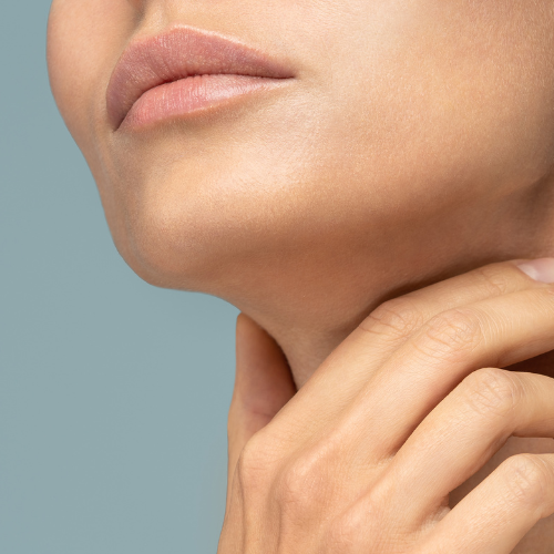 A close-up image of a person's lower face and neck. The person has a light skin tone and is seen placing their hand gently on their neck. The background is a solid light blue.