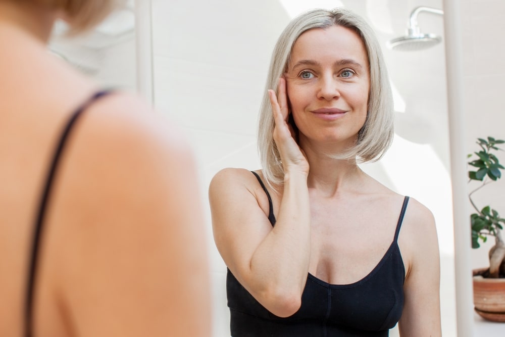 Blond Female Touching her face in a mirror