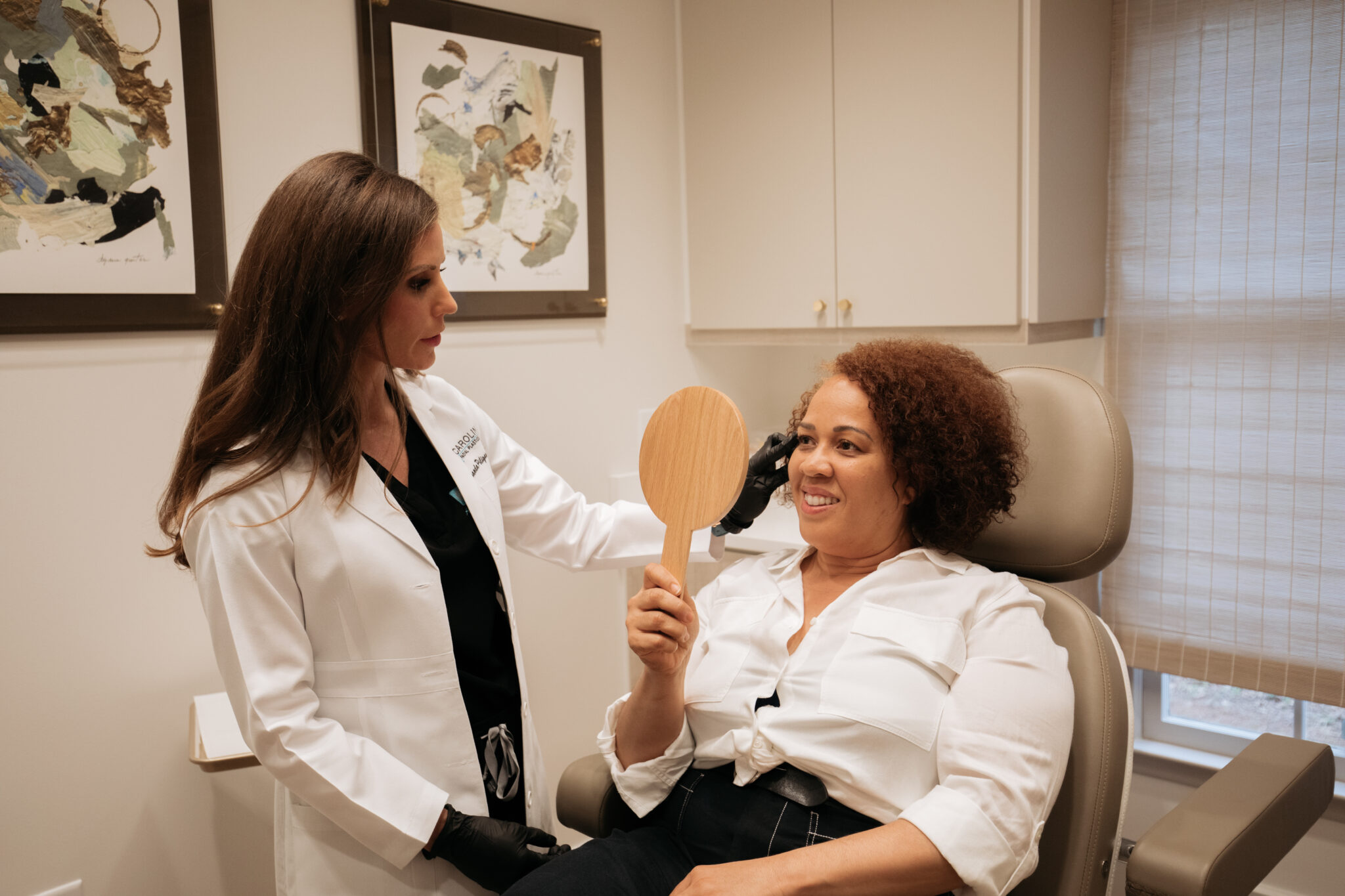 woman looking in a mirror seeing her results from laser treatment