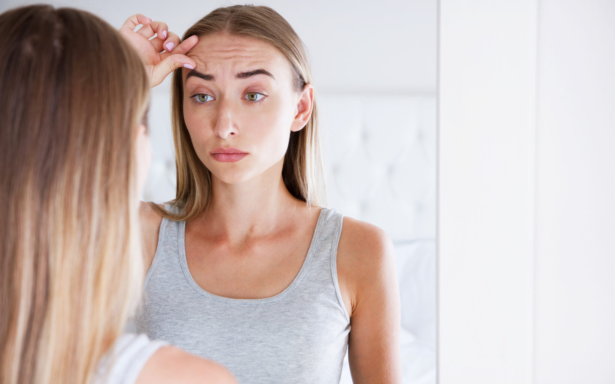 young woman concerned about wrinkles and fine lines on forehead and eyebrows
