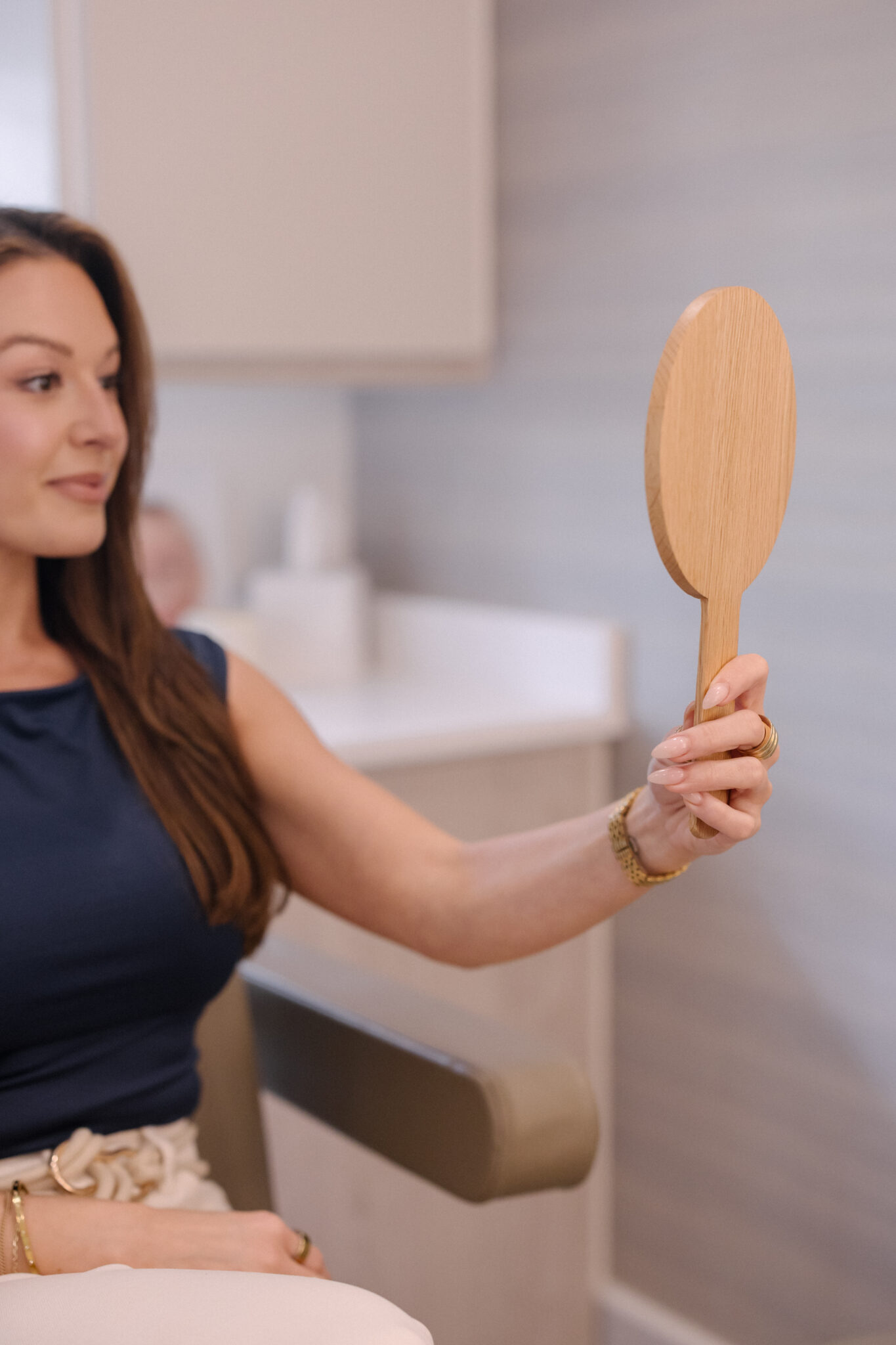 woman looking in the mirror seeing her facial plastic surgery results